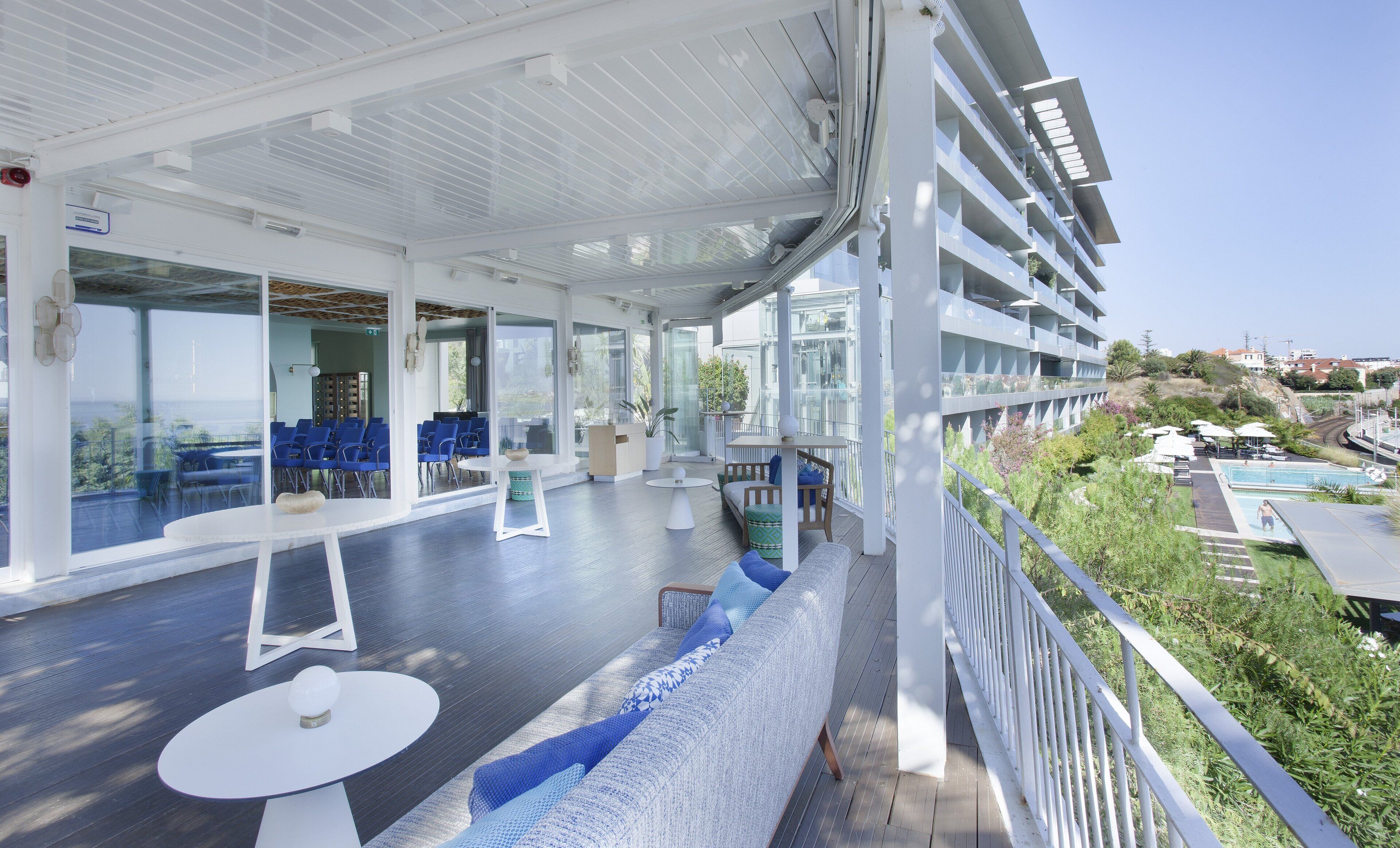 Un vaste espace extérieur aménagé avec des sièges et des tables, de grandes fenêtres et une vue sur le paysage environnant.