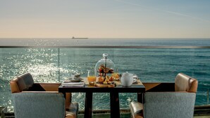 Une table dressée avec des aliments pour le petit-déjeuner, offrant une vue sur l’océan.