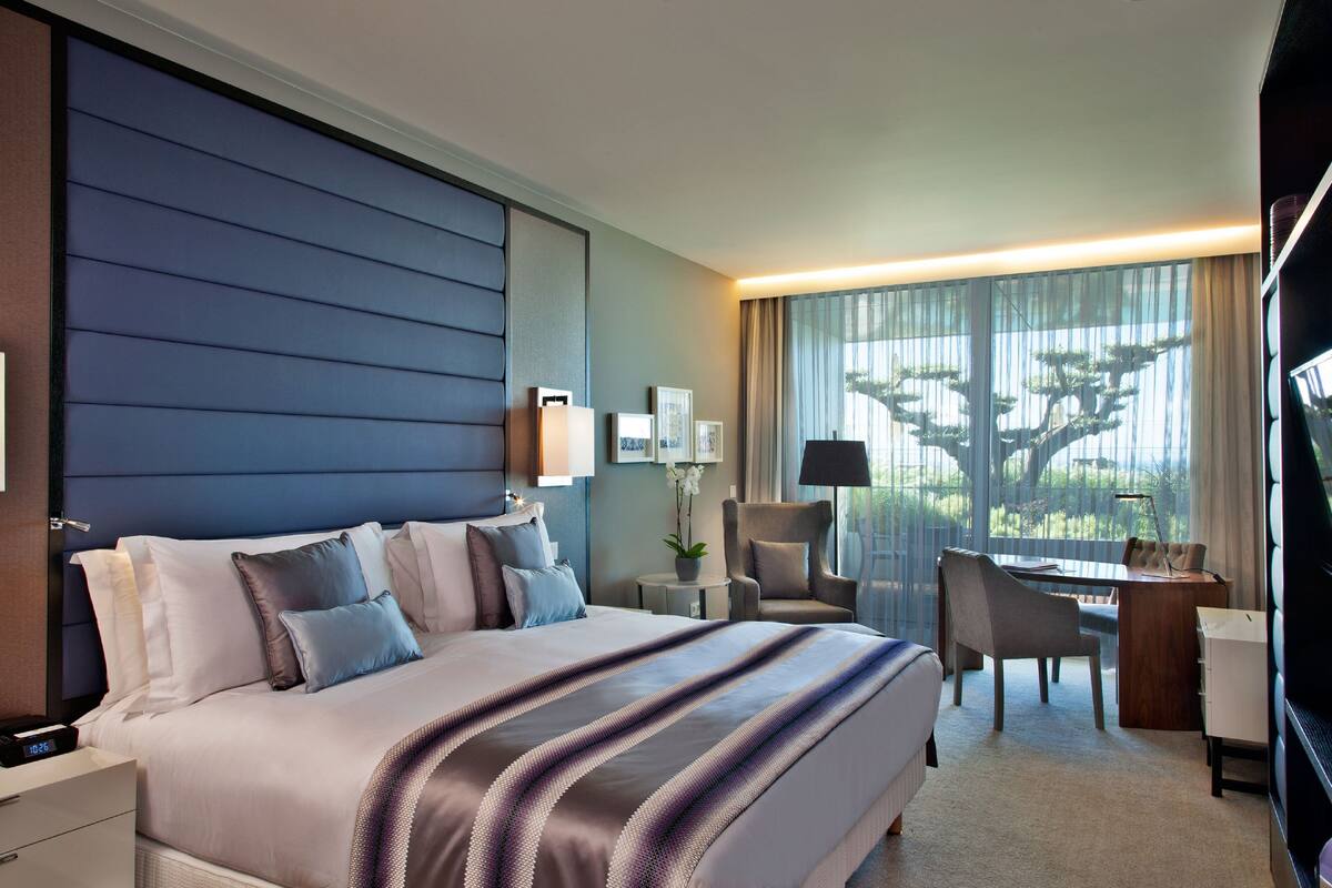 Ein modernes Hotelzimmer mit einem großen Bett, einem Schreibtisch und einem Sessel.