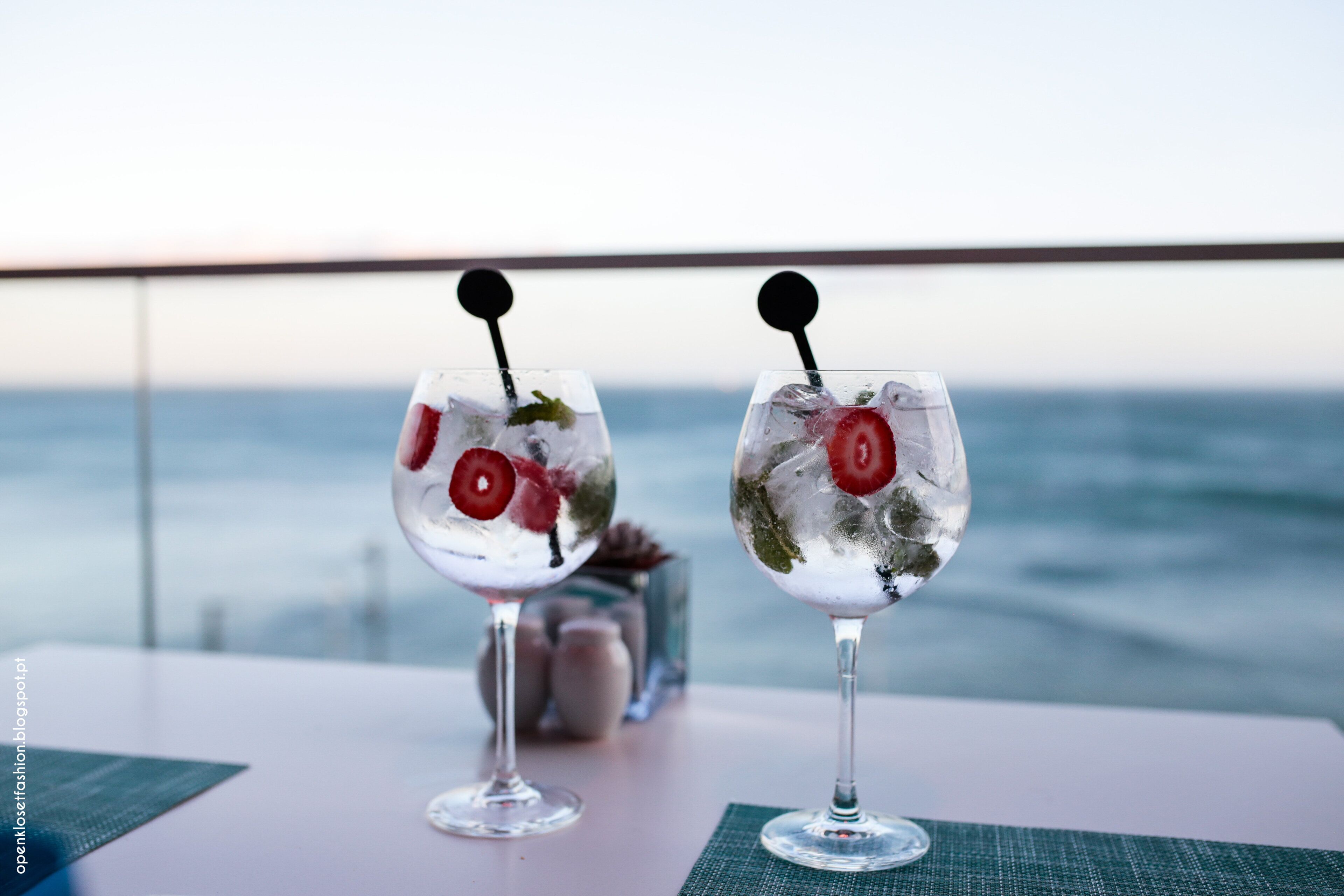 Dos vasos de bebidas heladas con adornos sobre una mesa con vista al mar.