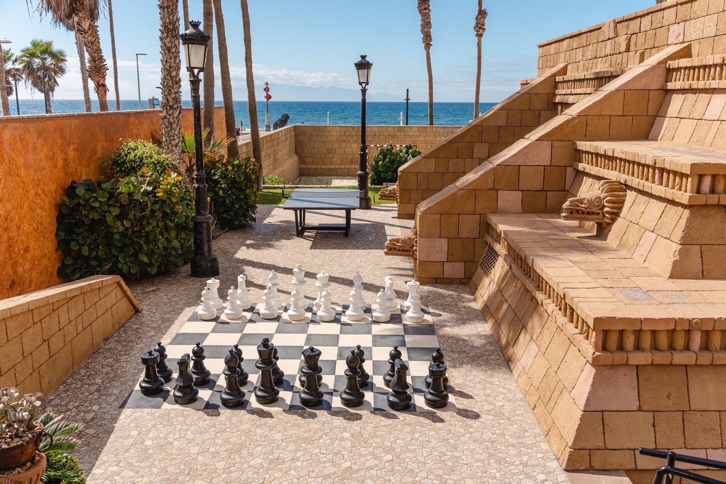 A chessboard set up outdoors with a view of the sea in the background.