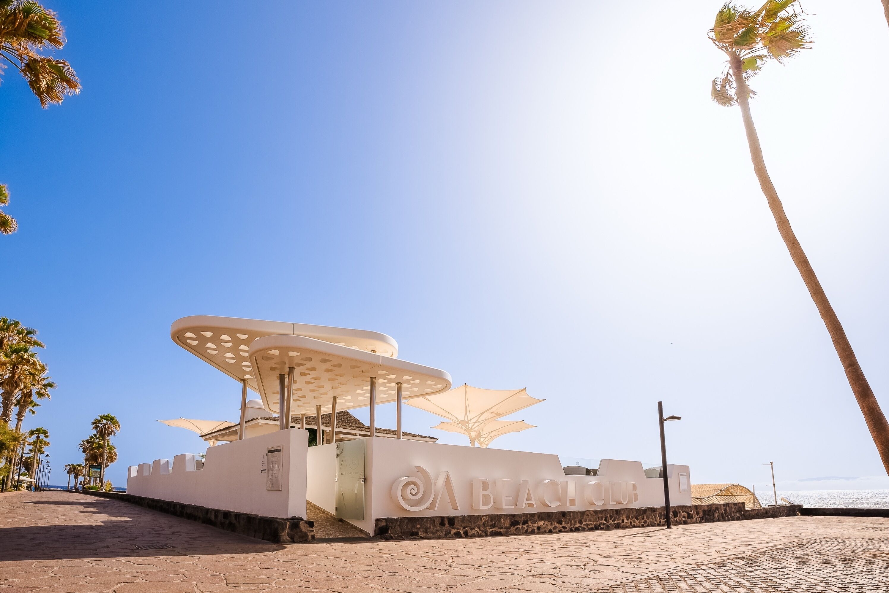 A beach club with a modern design, featuring a large umbrella and a sign that reads "Beach Club".