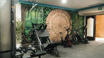 A gym with exercise equipment, a large mural, and a door marked 'SALIDA EXIT'.