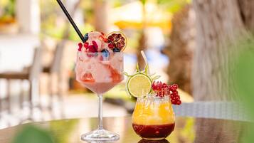 Two cocktails on a table with a blurred outdoor background.