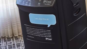 Um purificador de ar preto com painel de controle e uma balão de fala com a frase 'Vamos limpar o ar'.