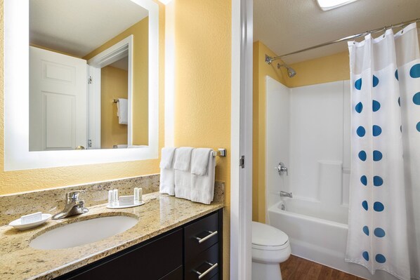 A bathroom with a sink, mirror, towel rack, and a shower curtain with blue polka dots.