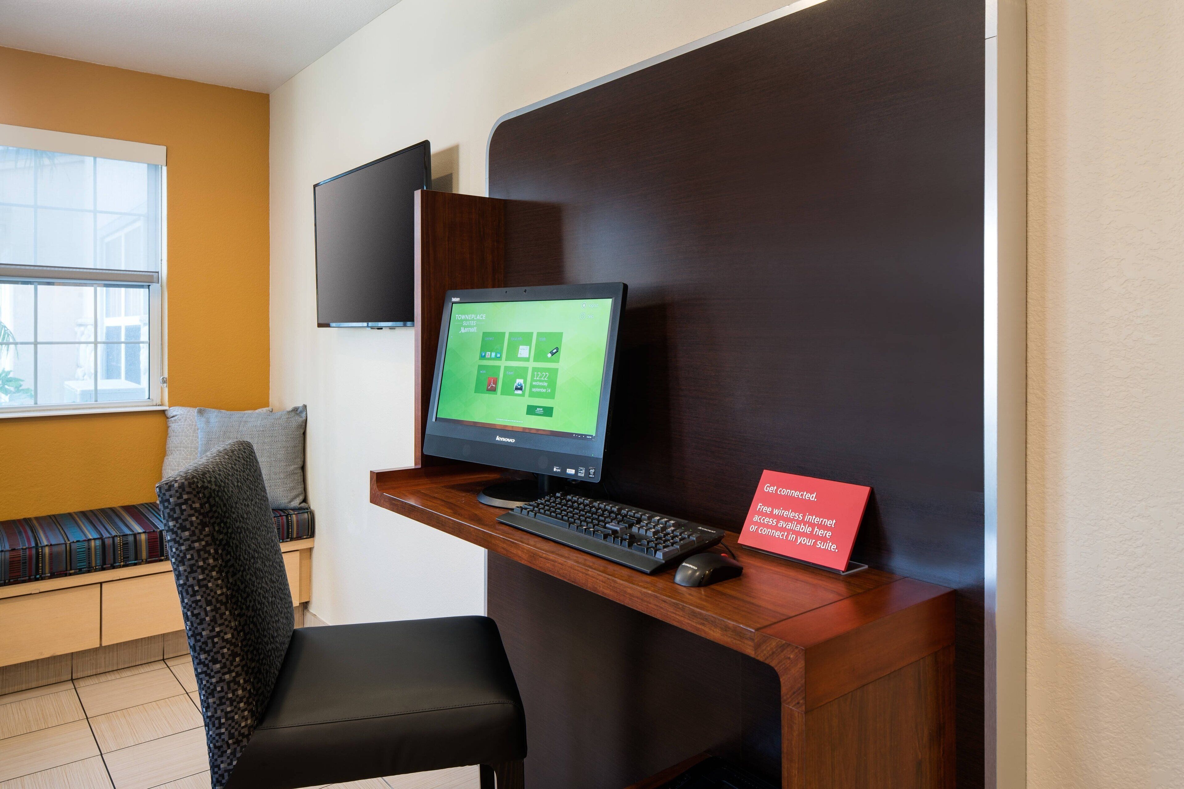 Een receptiebalie in een hotel, met een computer, toetsenbord, muis en een bordje dat gratis wifi aangeeft.
