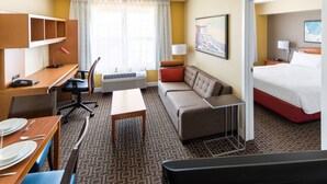 A hotel room with a desk, chair, sofa, and a bed.