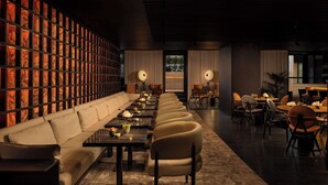 A modern lounge area with a sofa, chairs, tables, and a wall of illuminated panels. - art'otel Rome Via Veneto (Rome)