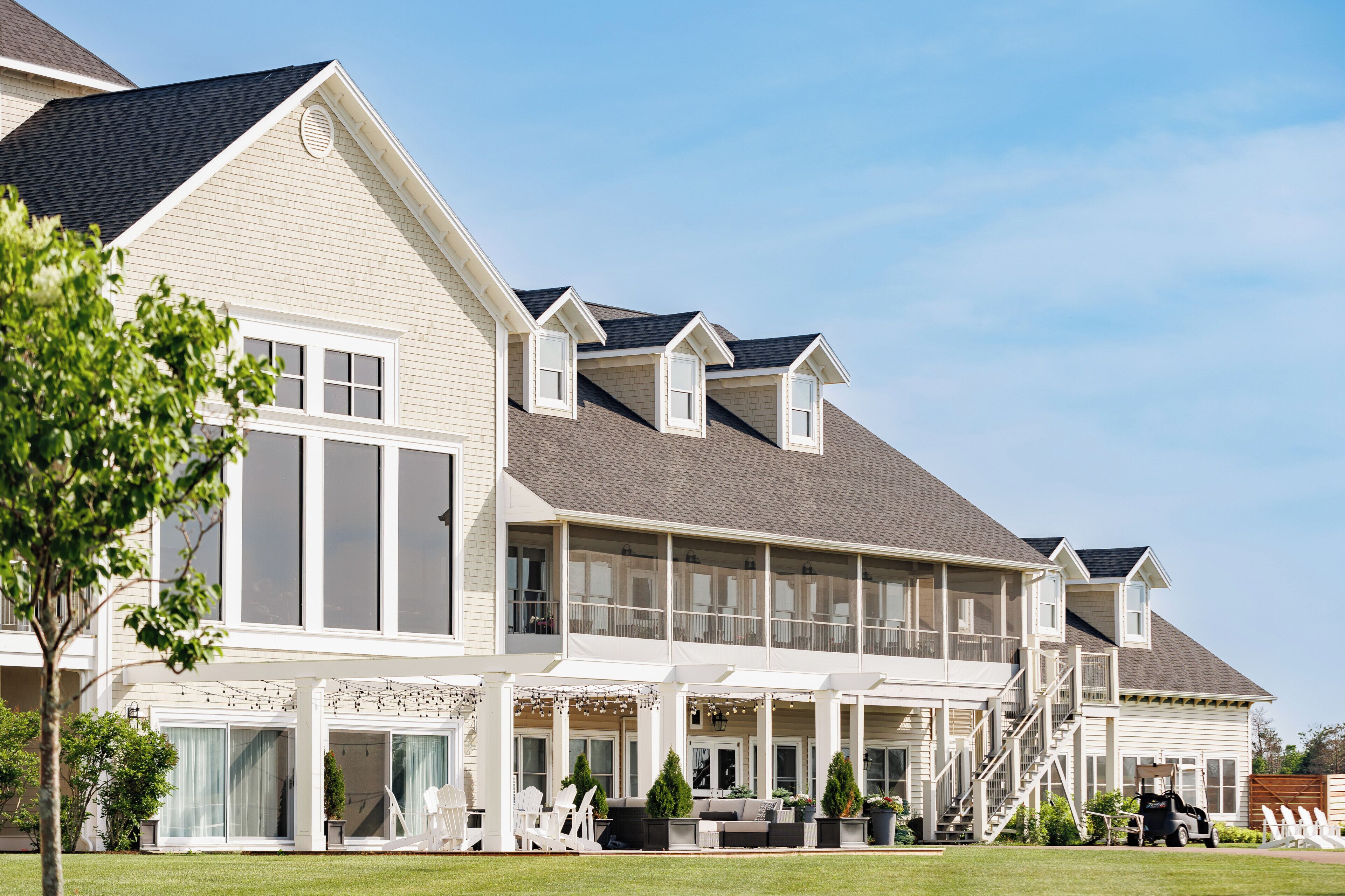 A multi-story residential building with a covered porch, large windows, and a well-maintained lawn.