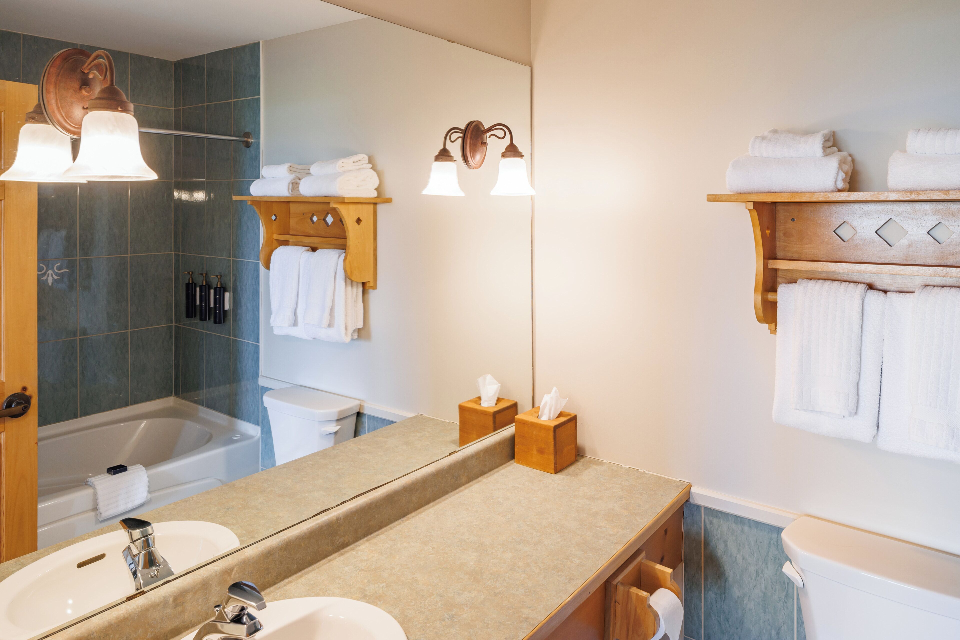 A modern bathroom with a large mirror, two sinks, a shower, and a towel rack.