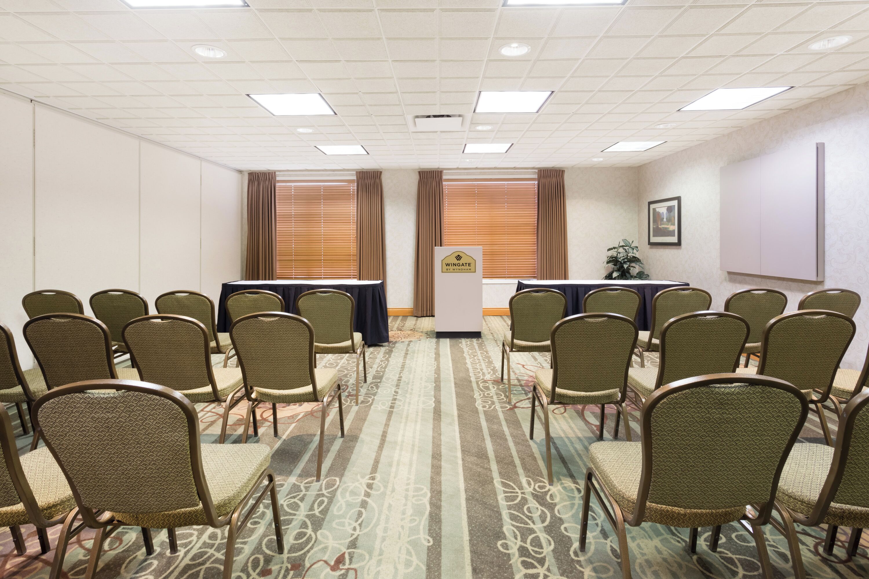 A conference room with rows of chairs, a podium, and a table with a blue tablecloth.