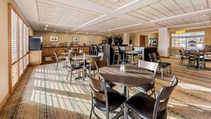 Un amplio vestíbulo de hotel con varias zonas de estar, una recepción y un ventanal grande que proporciona luz natural.
