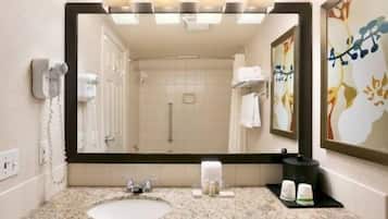 A bathroom with a large mirror, a sink, a towel rack, and a shower.