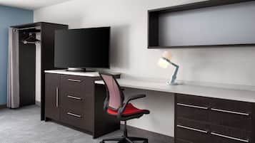 Un espacio de oficina moderno con escritorio, silla, televisor y armario.