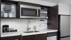 Une cuisine moderne avec des meubles en bois foncé, un four à micro-ondes en acier inoxydable, un lave-vaisselle et une machine à café.