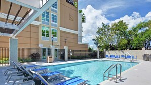 Un espace piscine d’hôtel avec des chaises longues et une piscine à l’eau d’un bleu limpide.