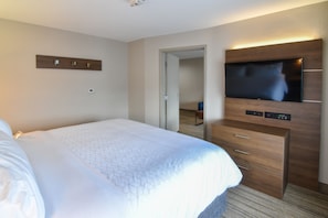 A hotel room with a large bed, a flat-screen TV mounted on the wall, and a wooden dresser with drawers. - Holiday Inn Express & Suites Indianapolis Northwest by IHG (Indianapolis)