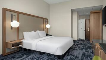 A hotel room with a large bed, bedside tables, a desk, and a television.