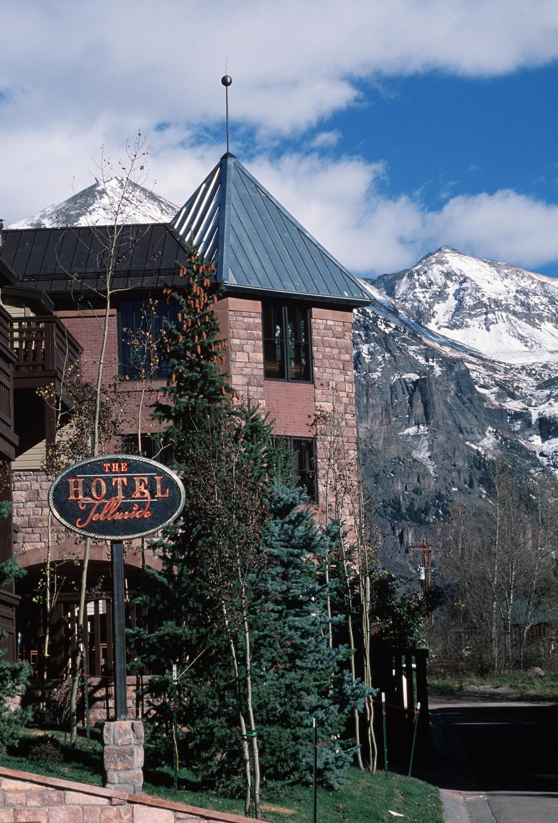Un hotel con montañas al fondo, un cartel que dice 'The Hotel Jimmie' y un techo de metal.