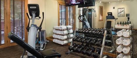 A gym with exercise equipment, towels, and a TV screen.