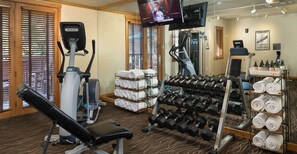 A gym with exercise equipment, towels, and a TV screen.