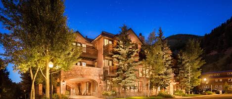 A multi-story hotel with a stone facade, multiple balconies, and a well-lit entrance.