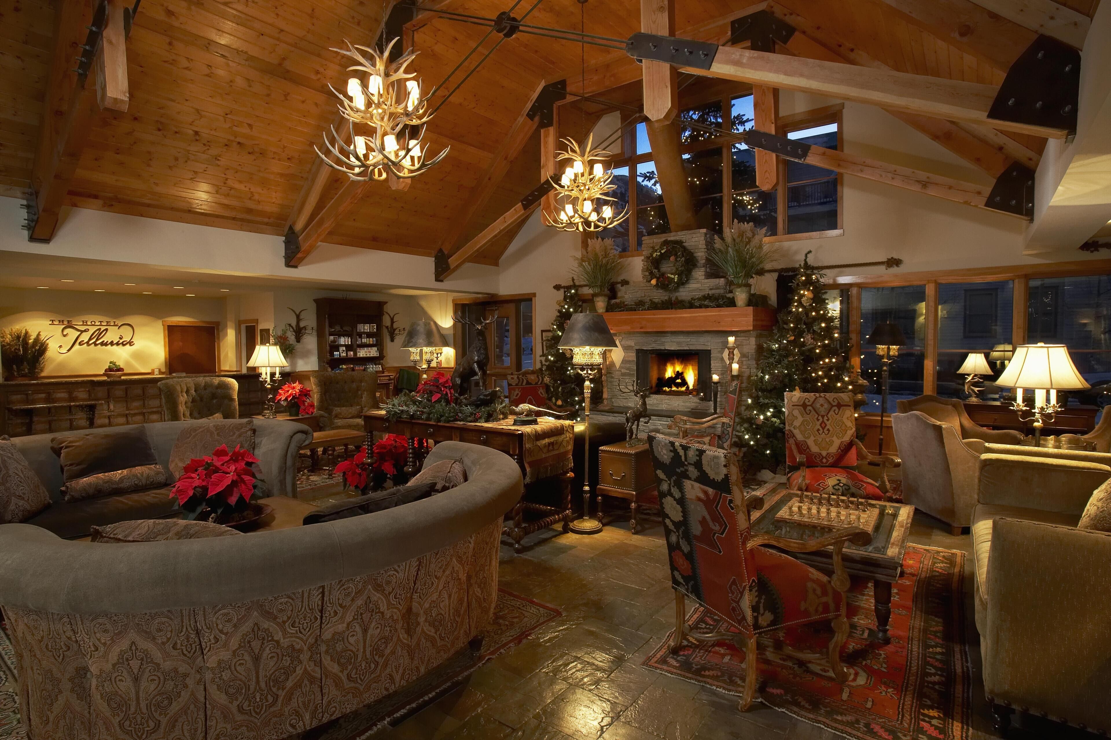 A cozy, well-lit living room with a fireplace, plush seating, and a Christmas tree.