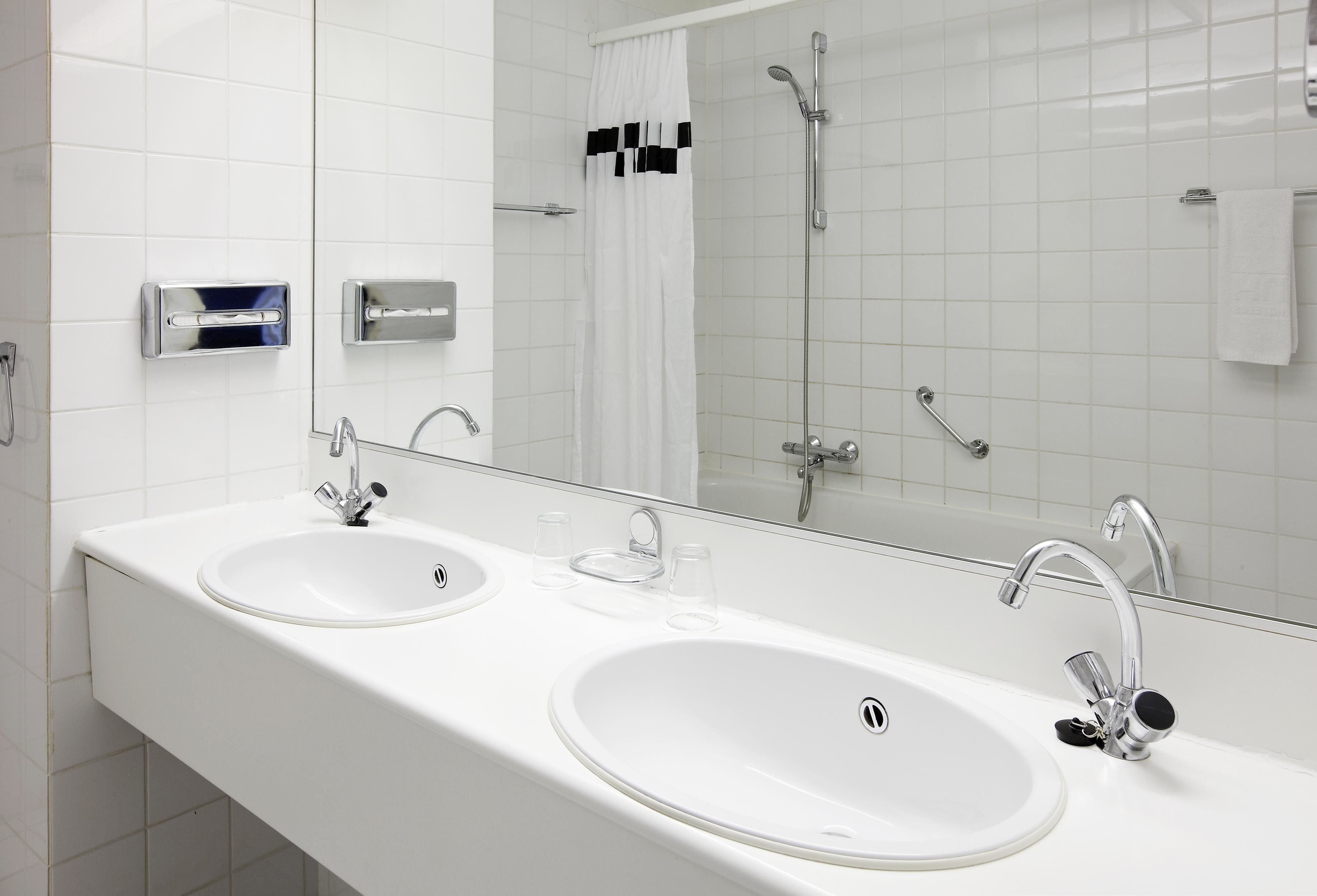 A modern bathroom with two sinks, a large mirror, and a shower.