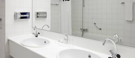A modern bathroom with two sinks, a large mirror, and a shower.