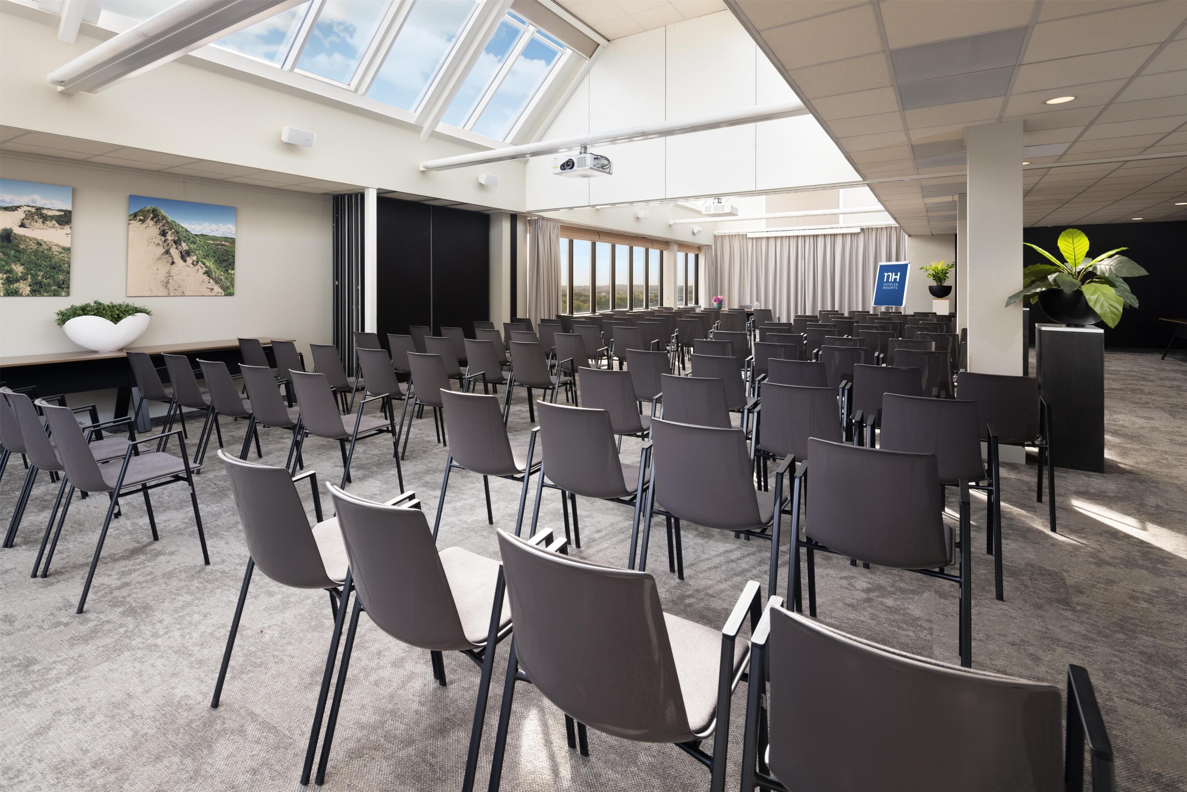 A conference room with rows of chairs, a projector, and large windows.