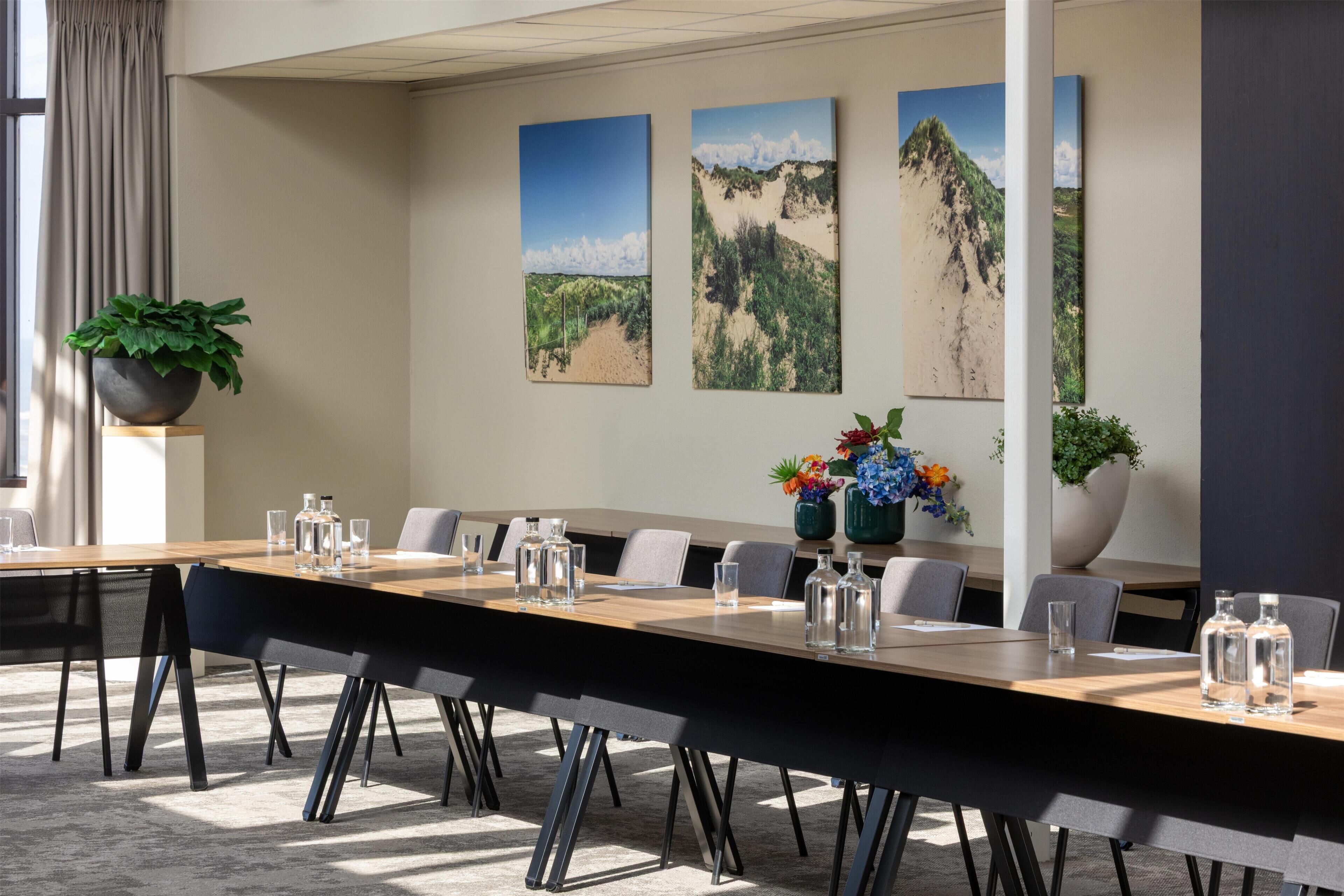 A conference room with a long table, chairs, and artwork on the walls.