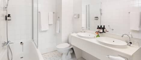 Un baño moderno con bañera, dos lavamanos, inodoro y ducha.