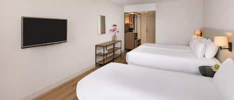 Una habitación de hotel con dos camas, televisión, una mesita y un espejo.