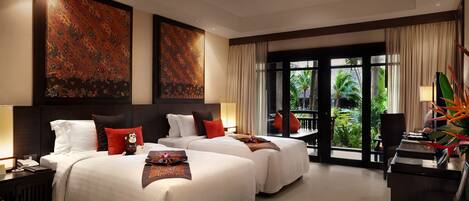 A hotel room with two beds, a desk, and a view of the outdoors.