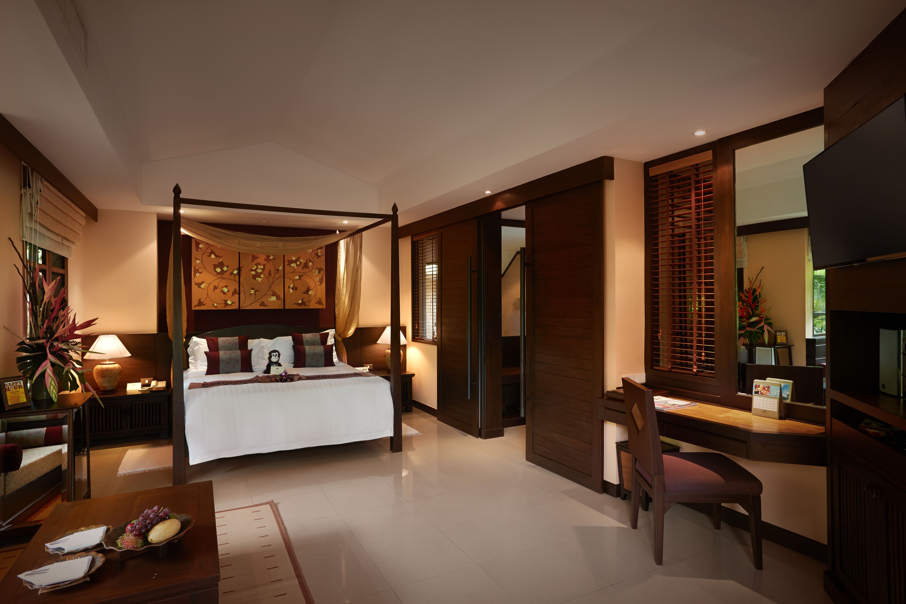 A modern hotel room with a large bed, a desk with a chair, a TV, and a bathroom with a shower and toilet.