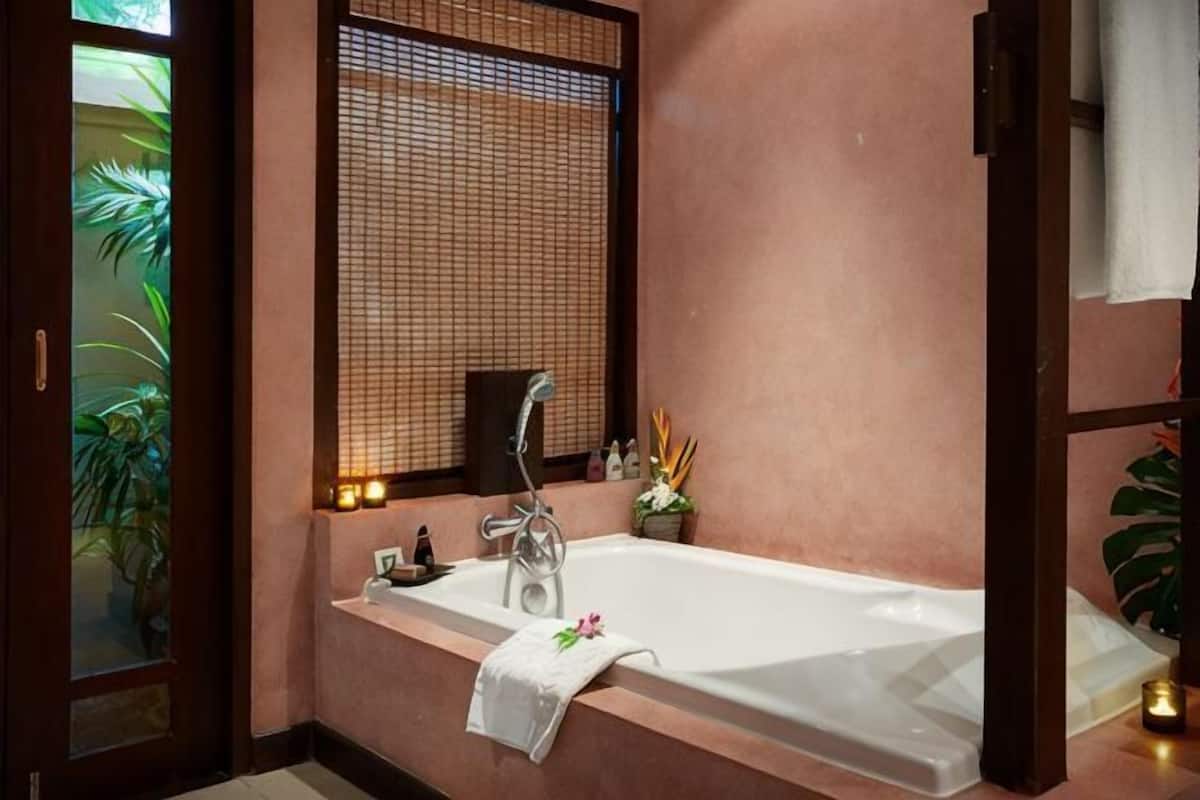 Un baño con una bañera, un espejo y una planta en maceta.