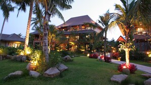 A resort with multiple buildings, lush greenery, and well-lit pathways. - Bo Phut Resort & Spa (Koh Samui)
