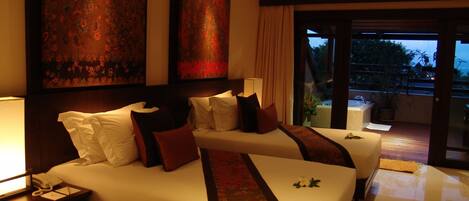 A hotel room with two beds, a nightstand with a telephone, and a large window with a view of the outdoors.
