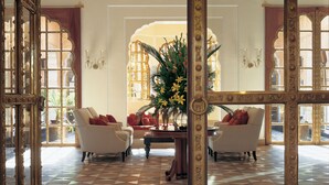 Un'imponente hall con pavimento a scacchi, specchi decorati e un lampadario.