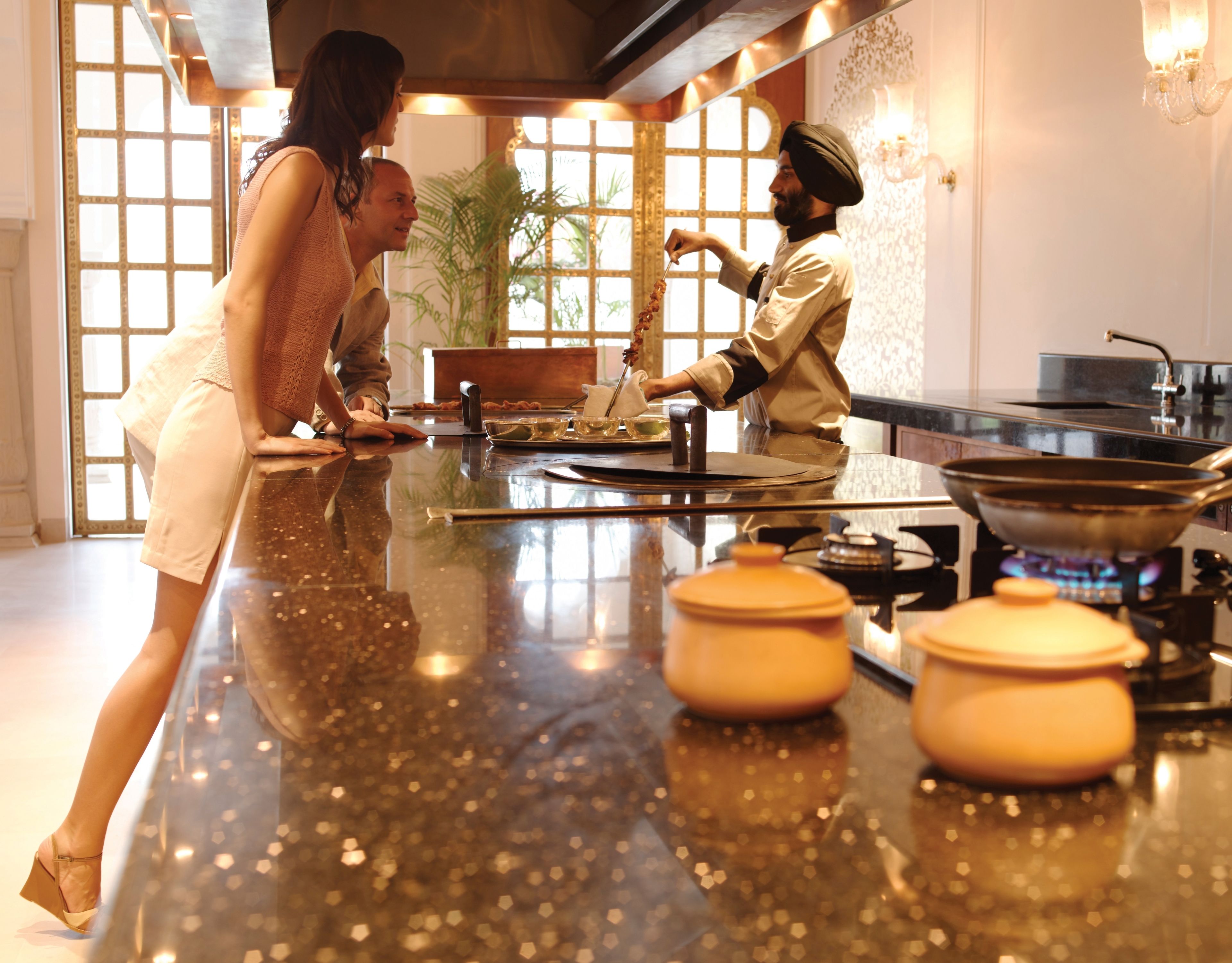 Une cuisine avec un plan de travail en marbre, une cuisinière et une personne qui cuisine.