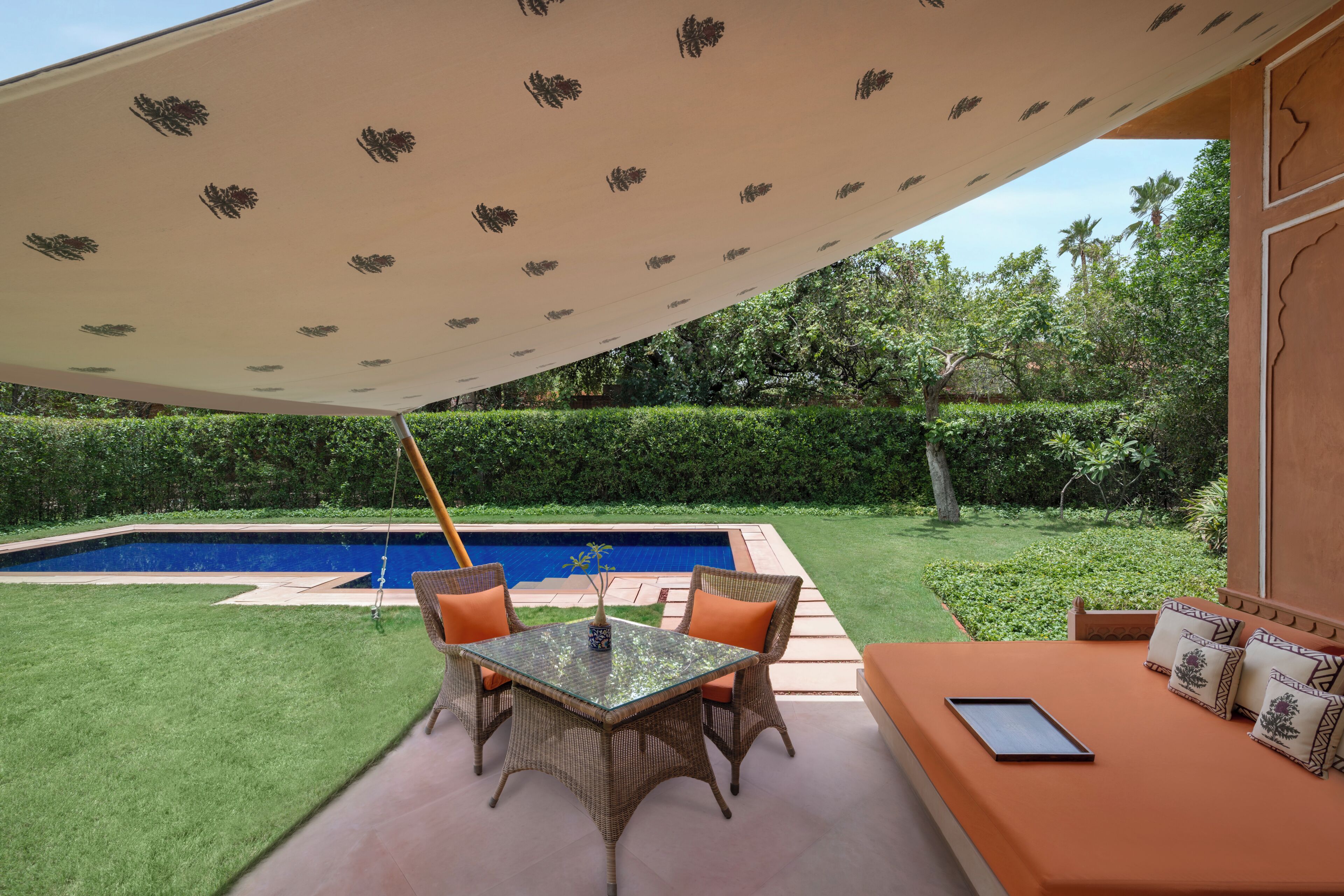 Un patio con tavolo e sedie, una piscina e un'area salotto con cuscini.