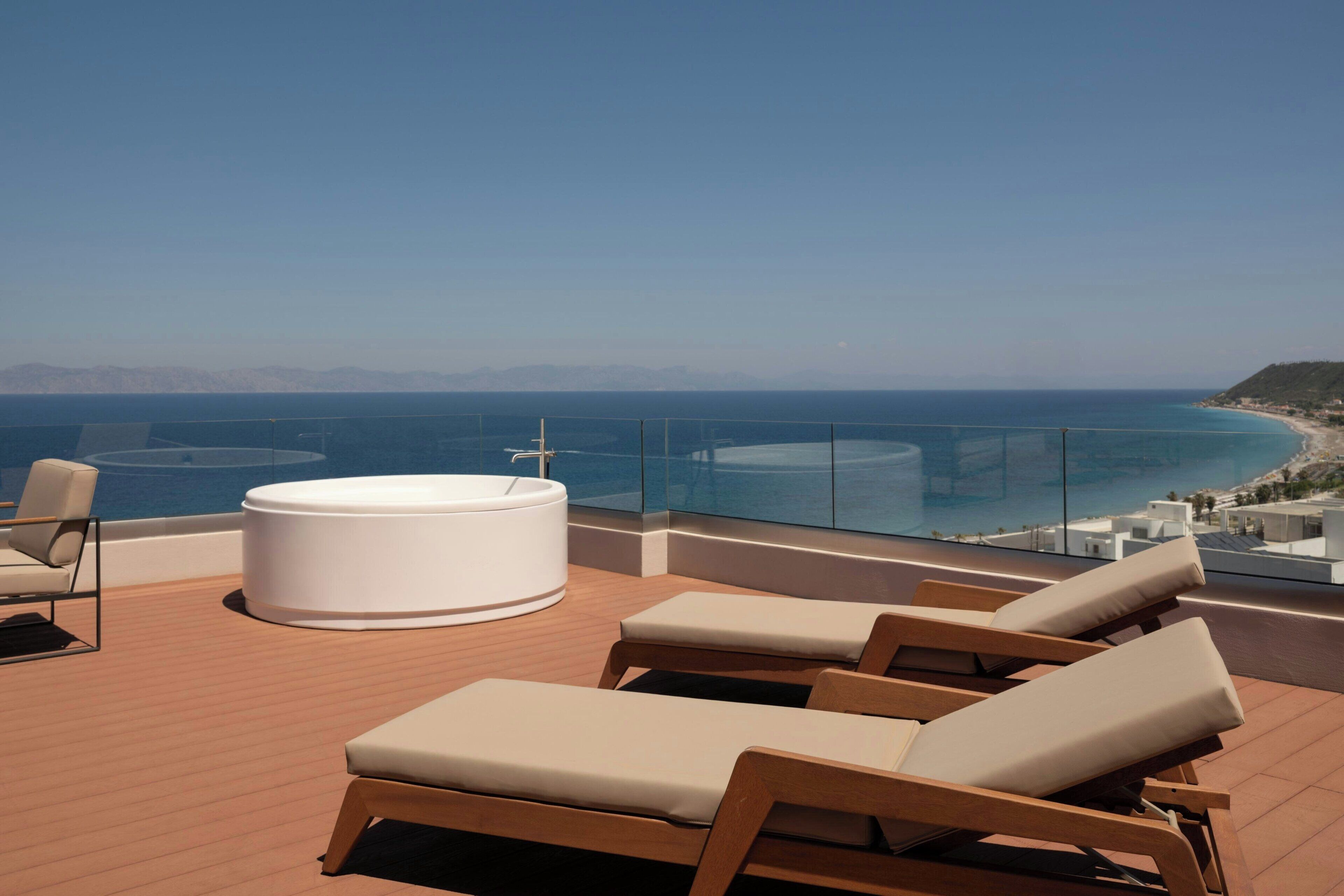 Una terraza en la azotea con hidromasaje, sillas de descanso y vista al mar.