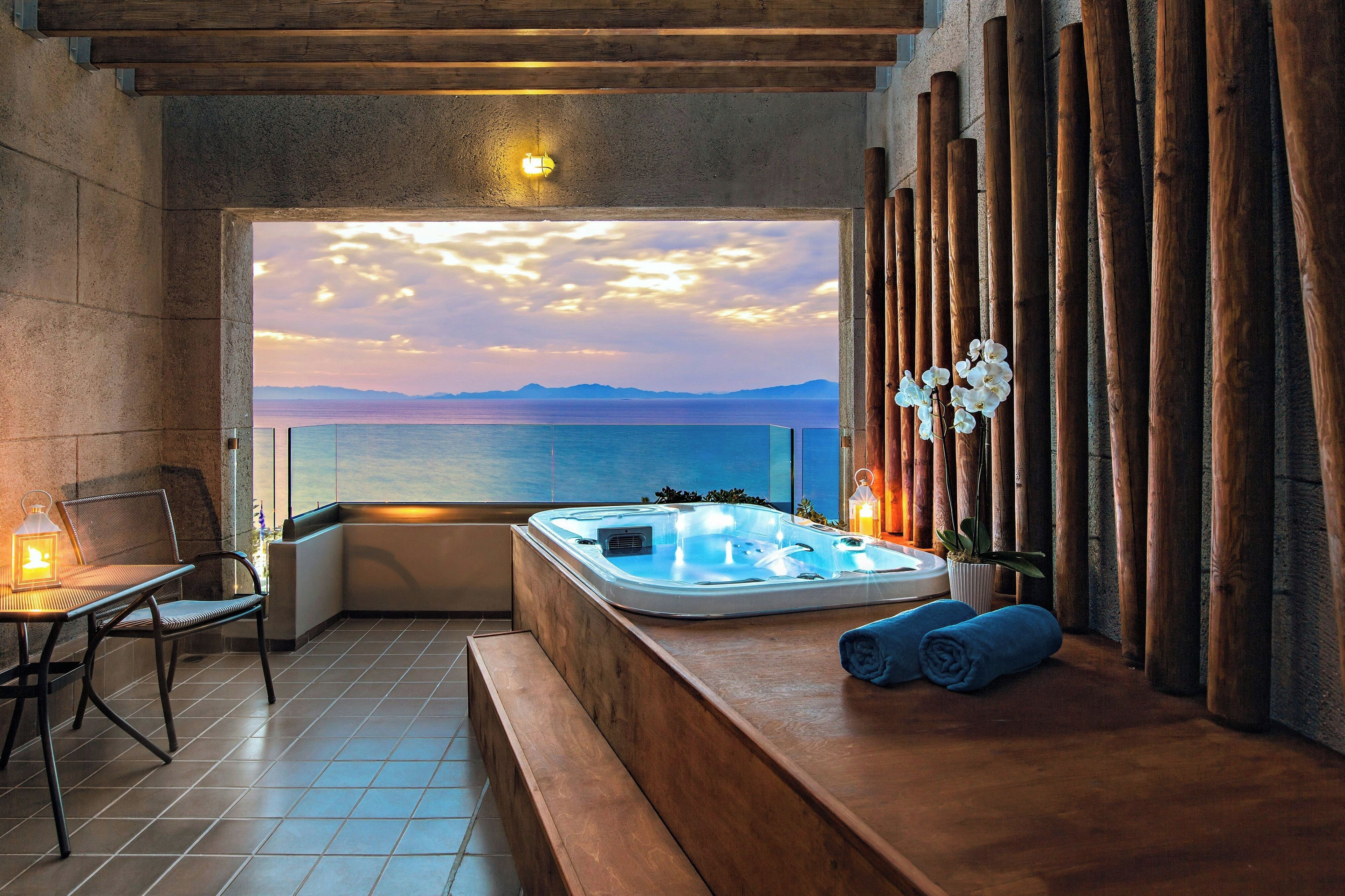 A spa area with a hot tub, seating, and a view of the sea.