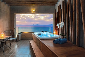 Ein Spa-Bereich mit Whirlpool, Sitzgelegenheiten und Meerblick.