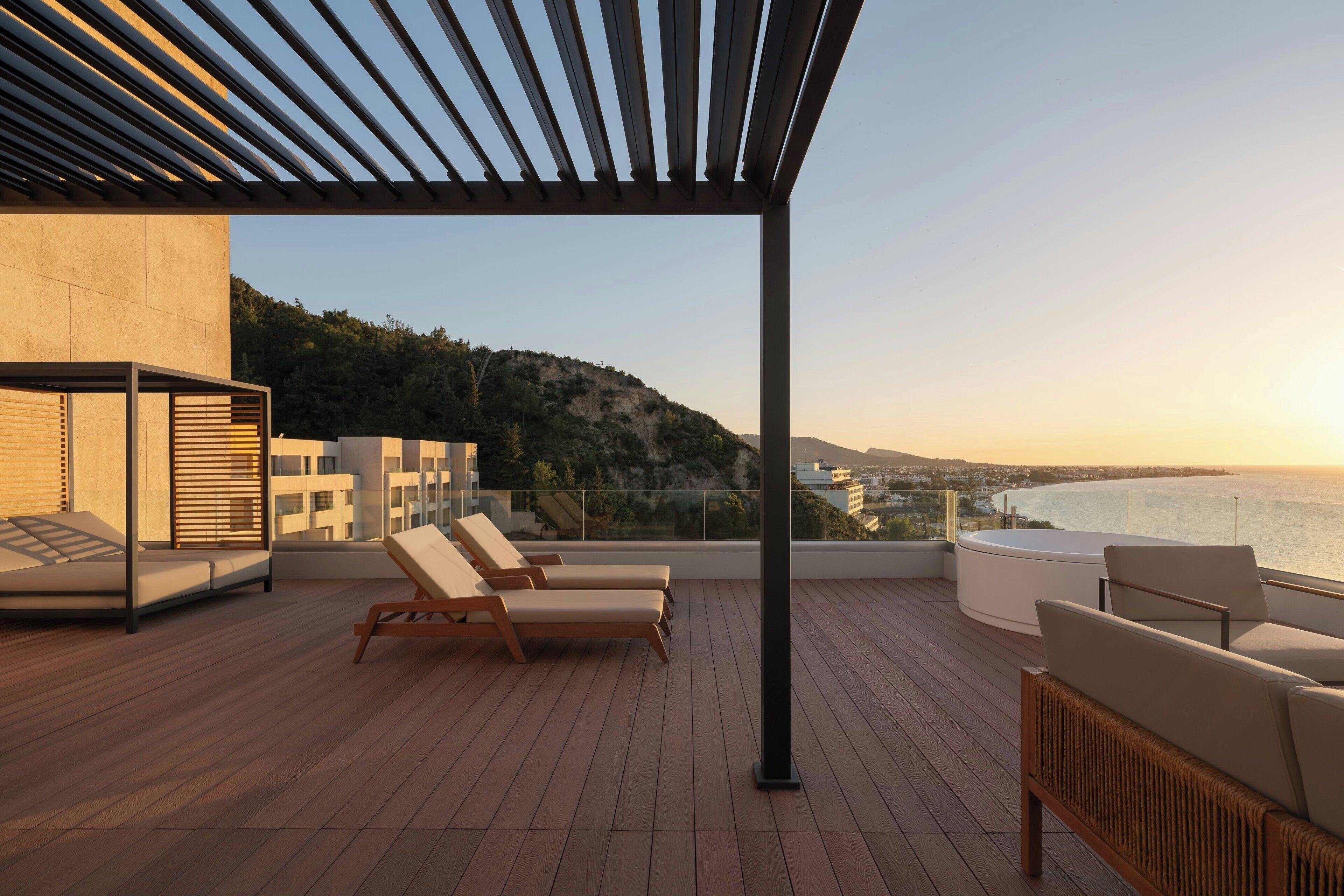 A rooftop terrace with lounge chairs, a hot tub, and a view of the sea.