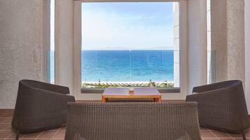 Un balcon agrémenté de meubles en osier, d’une table en bois et offrant une vue sur la mer.