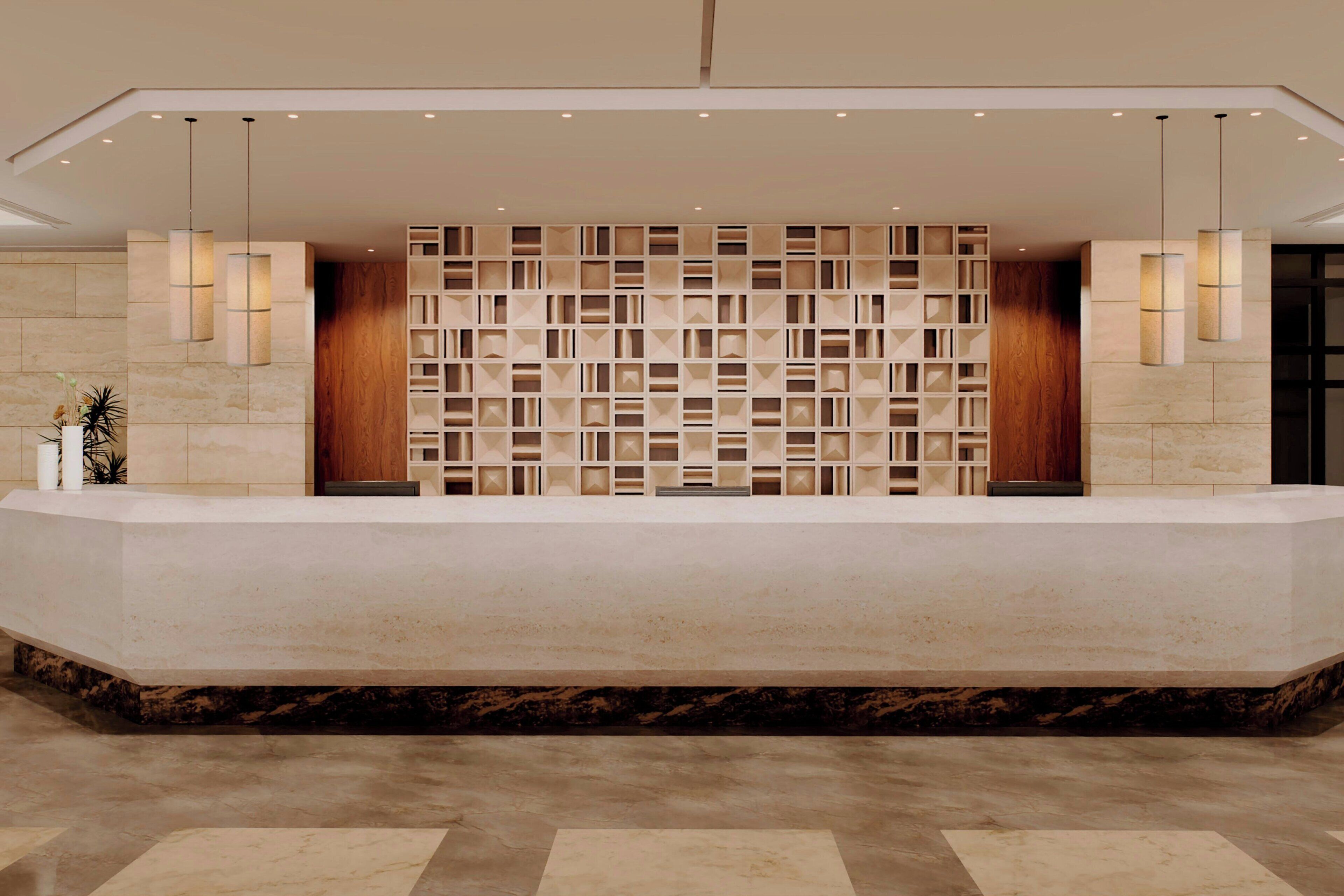 A reception desk with a marble base, a patterned wall, and pendant lighting.
