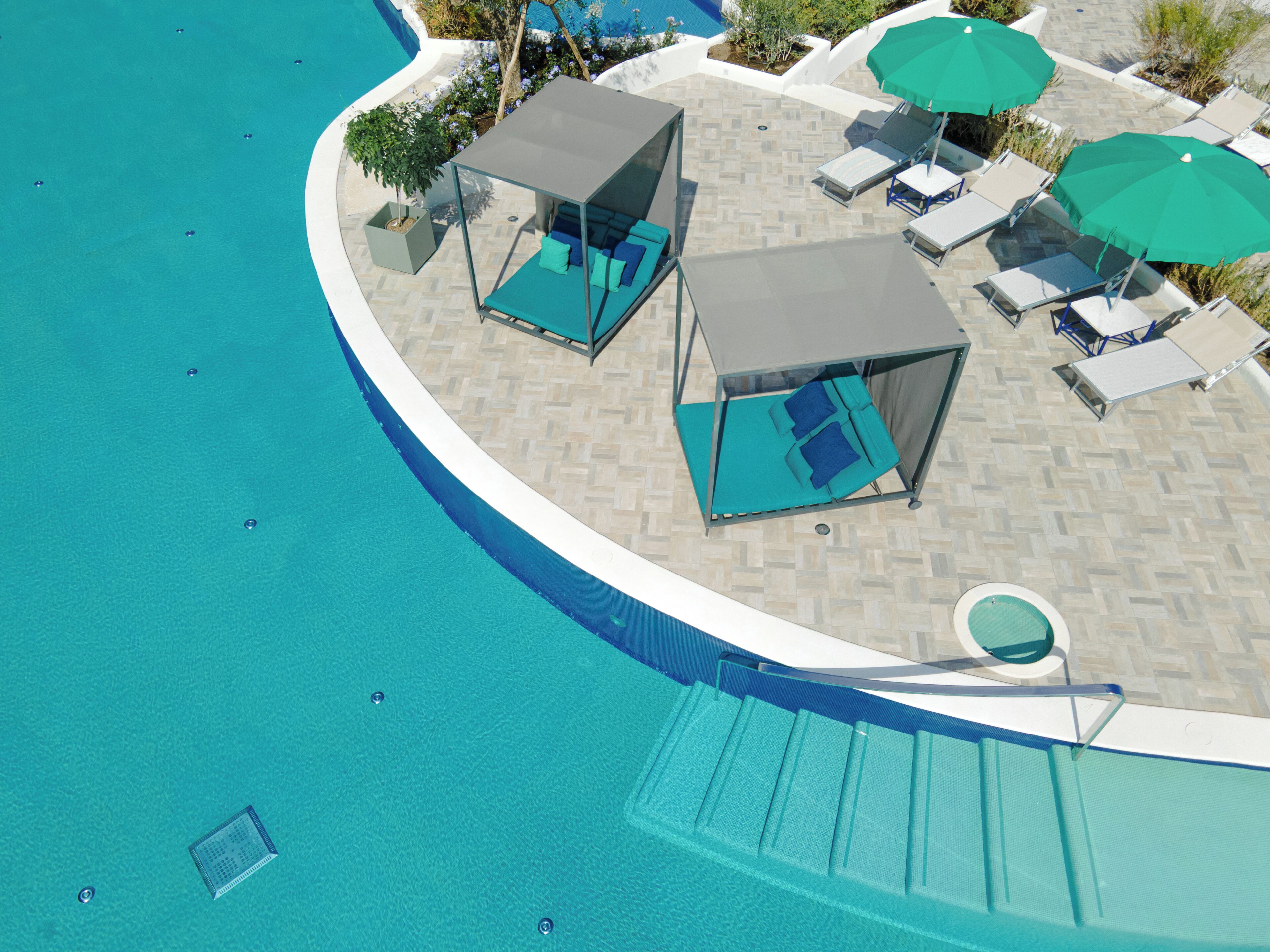 A poolside area with lounge chairs, umbrellas, and a covered seating area.