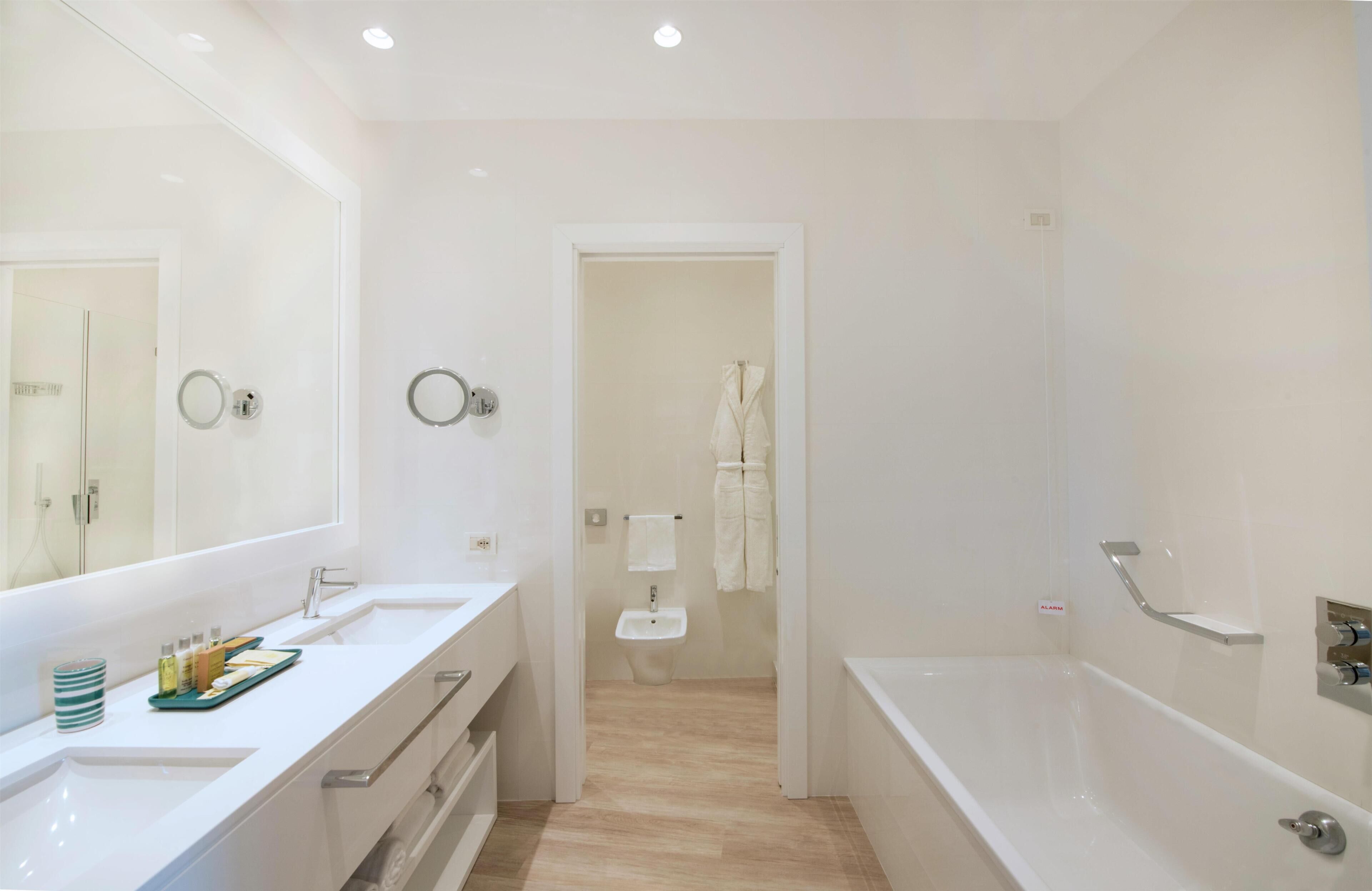 Un baño moderno con un espejo grande, dos lavamanos, una bañera y una ducha.